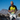 A male runner running outdoors with mountains and a blue sky in the background.