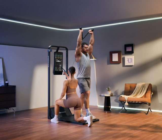 Two people use a Speediance Gym Monster 2 in a home gym setting