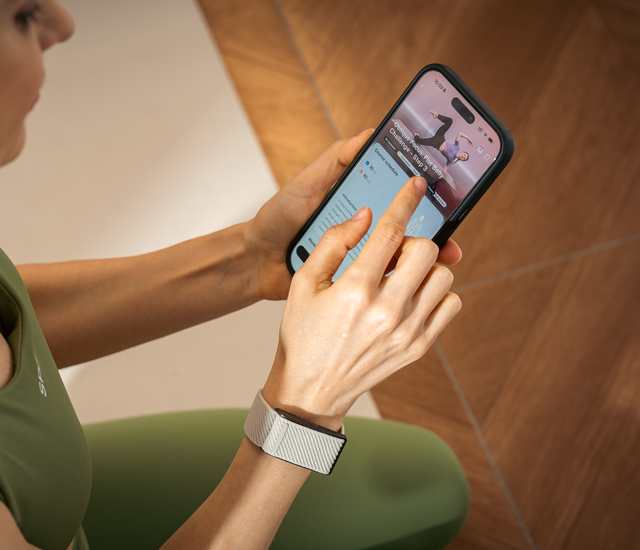 Walker comparing a phone and screen-free wrist tracker while paused outdoors
