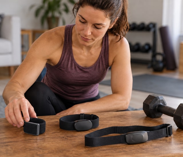 Adult preparing strength-training sensors beside a dumbbell
