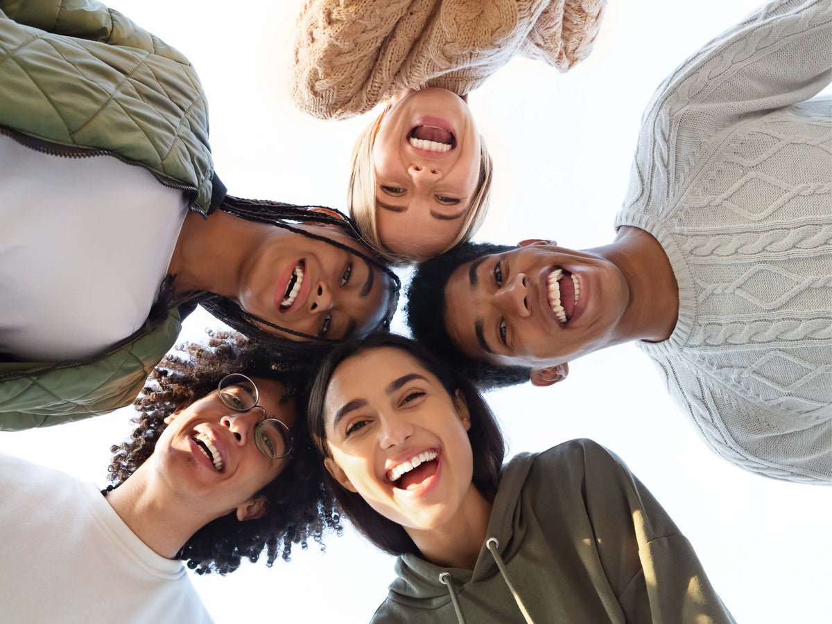 Five people standing in a circle and looking down, with a bright light source above them.