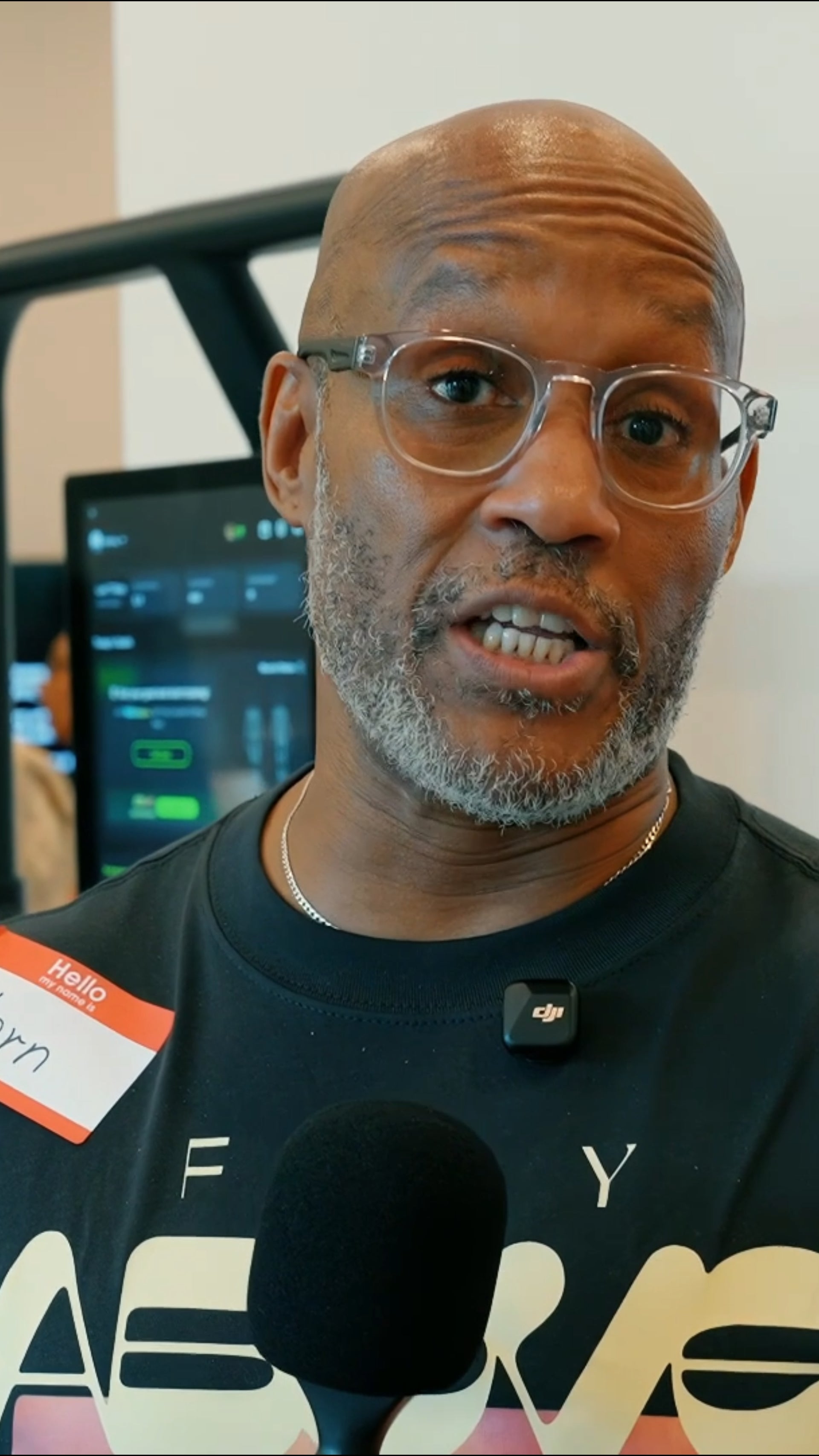 Man wearing glasses and a black shirt with a microphone in front of him
