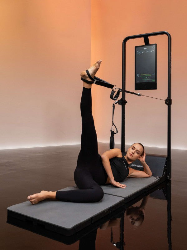 Person using Pilates reformer with app interface screen