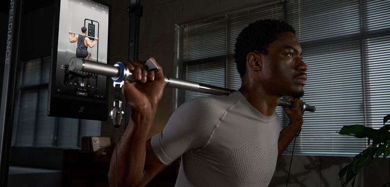 Person lifting weights with a mirror reflecting their form in a home gym setting.