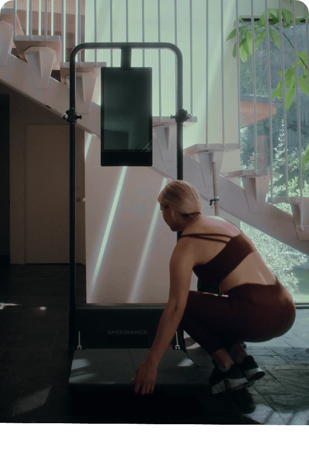 Person using a treadmill in a modern indoor setting with stairs and plants.